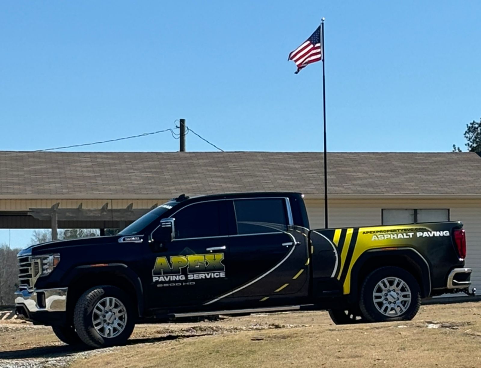 The black Apex Paving Service pickup with yellow asphalt paving striping